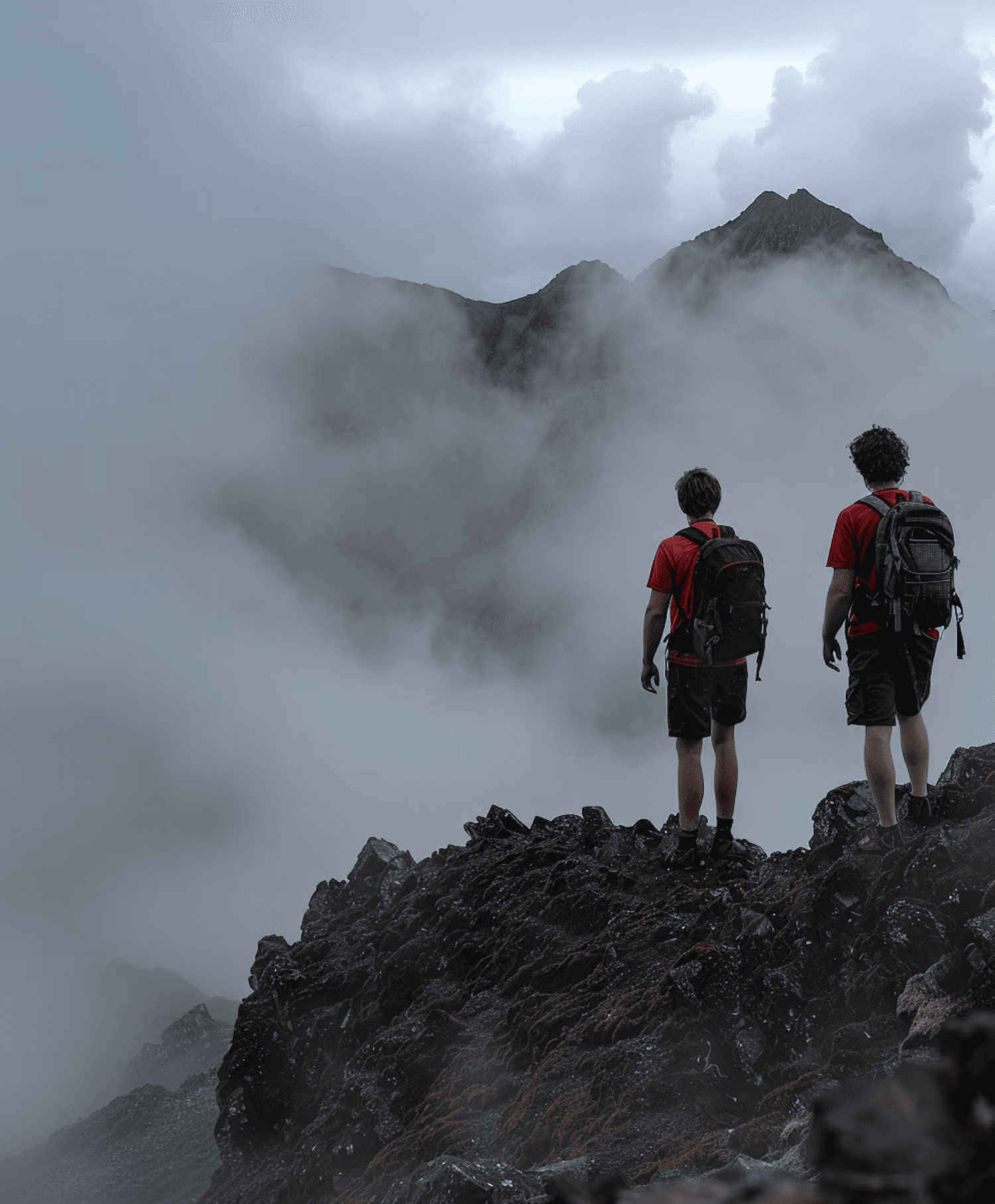 Two hikers overlooking a misty mountain landscape.